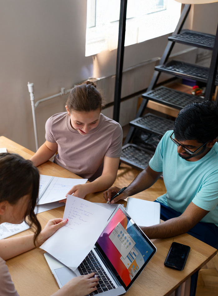 Students collaborating around a table with a laptop during a leadership activity