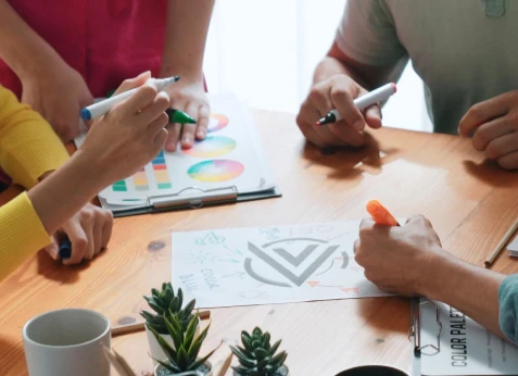 Students collaborating around a table with a colour palette during a creative workshop