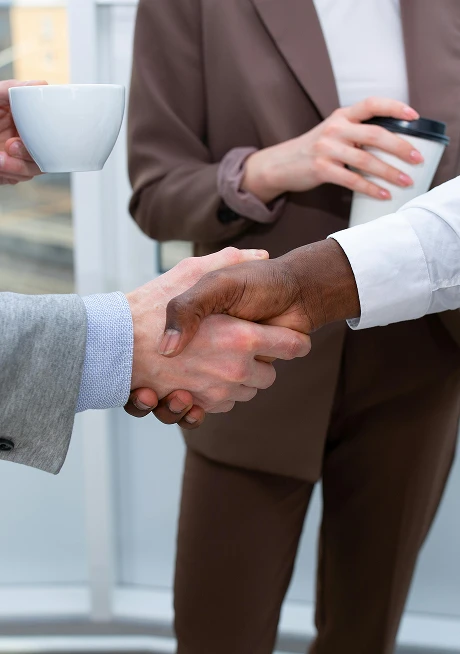 Partners shaking hands over coffee at WPU GŌA