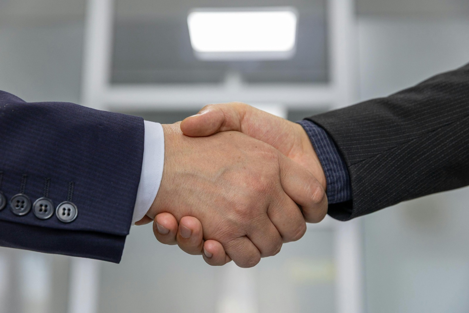 Two professionals shaking hands, symbolising community-anchored collaboration