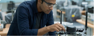A maker assembling a modular shelter component at a workbench